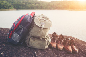 Backpacks and shoes with nature lake background.